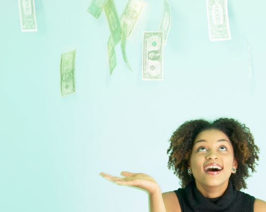 Smiling African American woman watching money fall