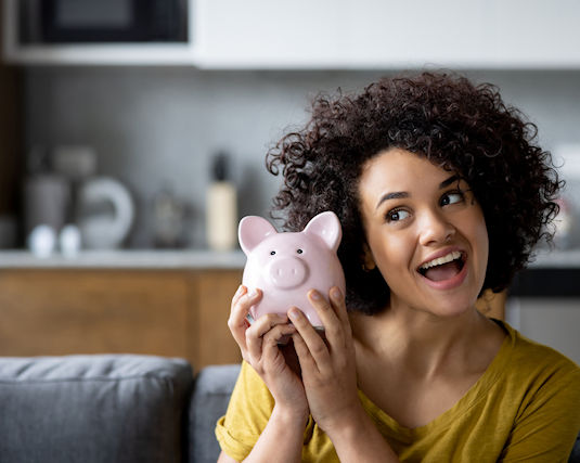 Portrait of a Latin American woman at home ready to open her piggy bank - home finances concepts